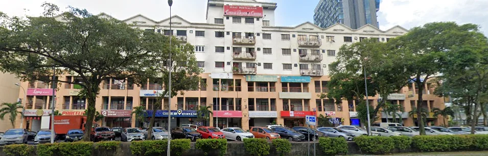 Exterior type: low-rise apartment block; features: cream painted facade, balconies with metal railings, ground floor retail spaces, multiple windows on upper floors, paved parking area, landscaped greenery in front, surrounded by palm trees, urban context with nearby buildings; style: modern.